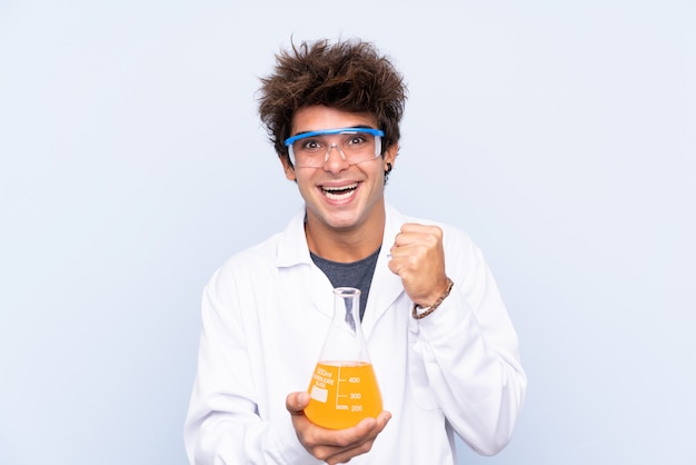 Jeune homme scientifique sur mur bleu isolé célébrant une victoire