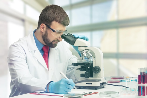 Jeune homme scientifique travaillant avec microscope