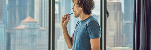 Jeune homme se brossant les dents dans sa salle de bain BANNIÈRE, format long