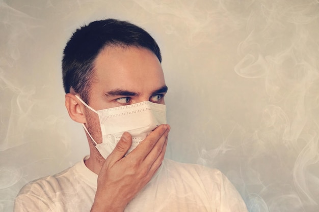 Un jeune homme se couvre le nez dans un masque Mauvaise odeur la puanteur le Concept de fumée de quarantaine recouvrant le concept de pollution de l'air et de l'environnement
