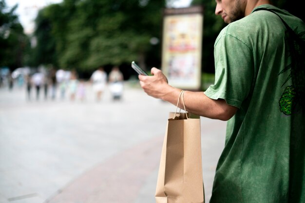 Un jeune homme se déplace dans la ville avec un sac en papier, livraison de produits