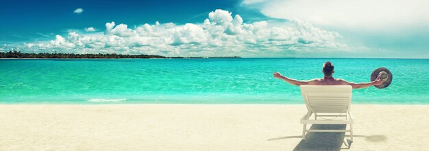 Jeune homme se détendre dans une chaise longue sur la plage. Fond de vacances.