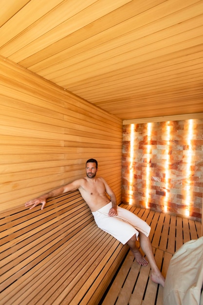 Jeune homme se détendre dans le sauna