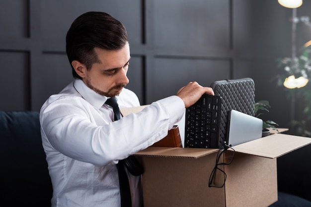 Un jeune homme se fait virer de son travail. Homme d'affaires et boîte en carton avec ses effets personnels d'un lieu de travail.