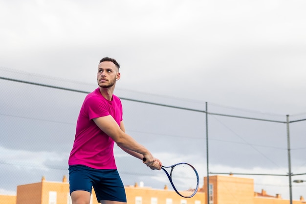 Un jeune homme se prépare à un coup de revers au tennis.
