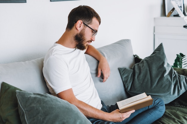 Jeune homme se reposant sur un canapé et lisant un livre