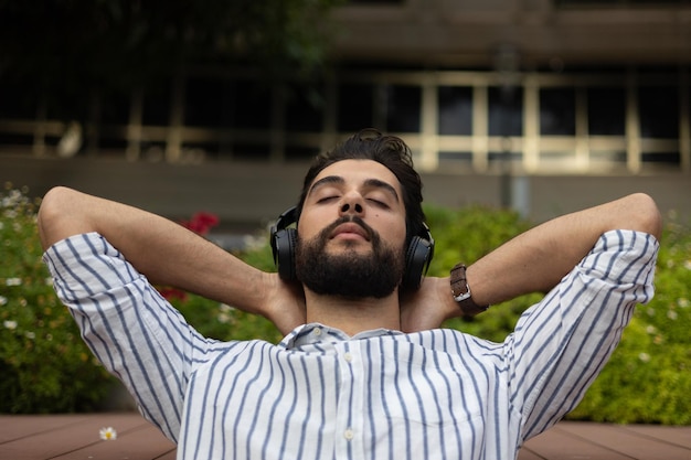 Jeune homme se reposant en écoutant de la musique avec ses bras sur sa tête