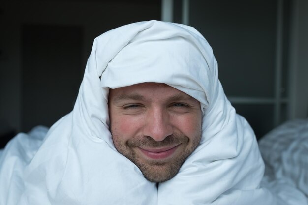 Photo jeune homme se réveillant le matin de bonne humeur souriant après un bon rêve