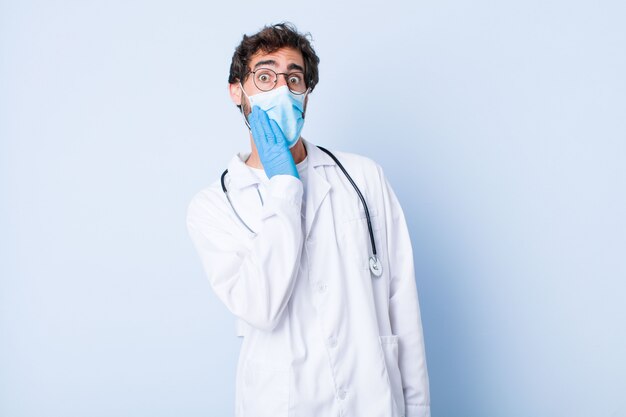 Jeune homme se sentant choqué et étonné, tenant l'incrédulité face à main avec la bouche grande ouverte. concept de coronavirus