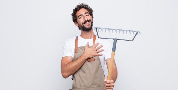 Jeune homme se sentant heureux et amoureux, souriant d'une main à côté du cœur et de l'autre tendu à l'avant