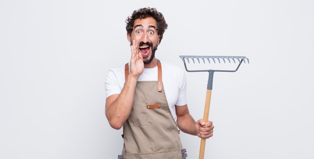 Jeune homme se sentant heureux, excité et positif, donnant un grand cri avec les mains à côté de la bouche, appelant