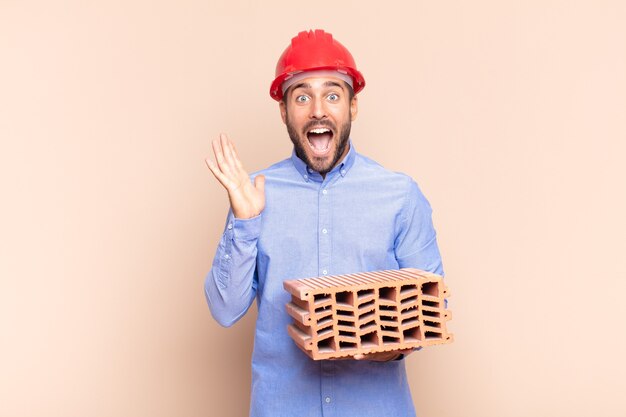 Jeune homme se sentant heureux, excité, surpris ou choqué, souriant isolé