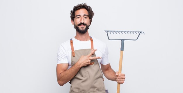 Jeune homme se sentir heureux, positif et réussi, avec la main en forme de v sur la poitrine, montrant la victoire ou la paix