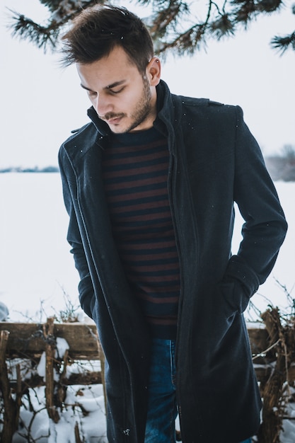 Jeune homme séduisant, embrassant la neige en hiver.