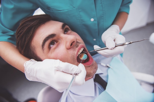 Jeune homme séduisant sur un examen du médecin dentiste Gros plan