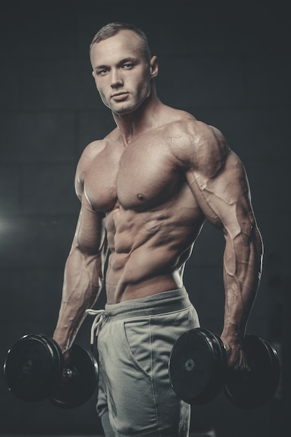 Jeune homme séduisant modèle de formation dans la salle de gym