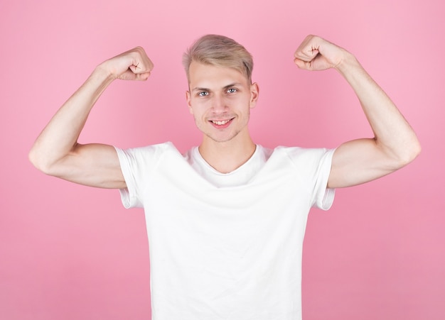 Jeune homme séduisant montrant ses biceps après la remise en forme.