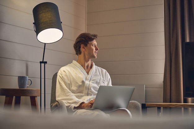 jeune homme séduisant portant un peignoir blanc tout en se concentrant sur le travail