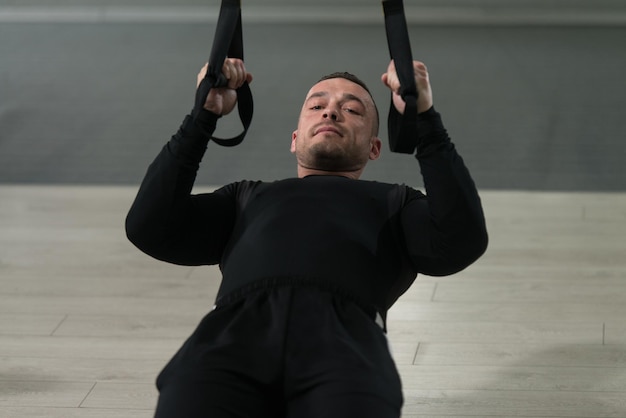 Jeune homme séduisant s'entraînant avec des sangles de fitness Trx