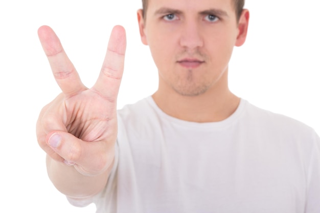 Jeune homme séduisant en t-shirt blanc montre un signe de paix isolé sur fond blanc