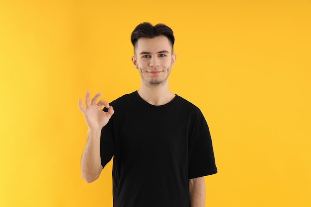 Jeune homme séduisant en t-shirt sur fond jaune