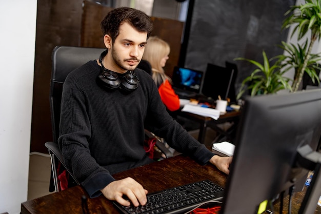 Jeune homme sérieux concentré sur le problème sur l'écran du PC Le programmeur intelligent travaille dur dans l'entreprise informatique à l'intérieur