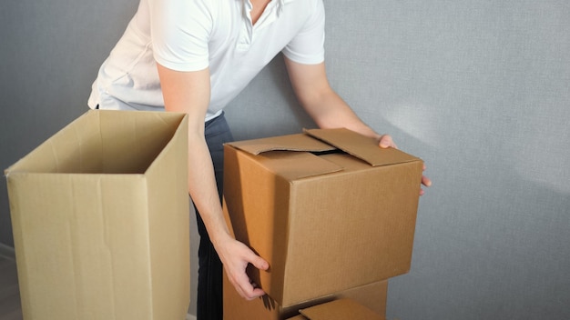 Jeune homme de service de livraison transportant des boîtes dans une nouvelle maison le jour du déménagement, espace de copie