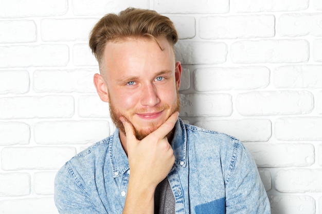 Jeune homme sexy contre un mur de briques blanches