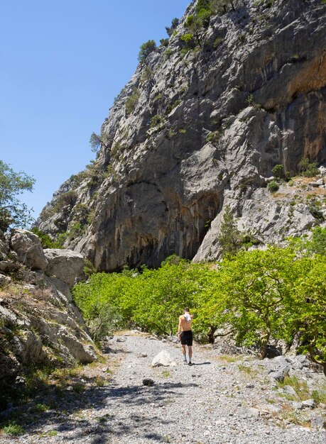 Un jeune homme en short et une casquette de baseball se promène dans une gorge de montagne en Grèce