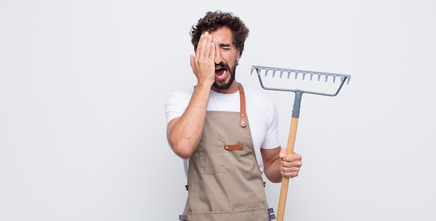 Jeune homme à la somnolence, s'ennuie et bâillements, avec un mal de tête et une main couvrant la moitié du visage