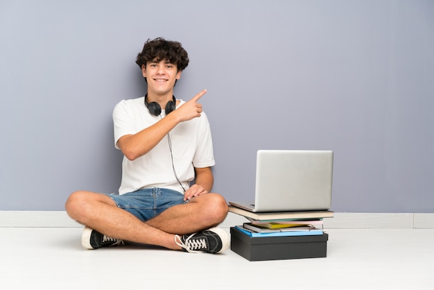 Jeune homme avec son ordinateur portable assis un le sol