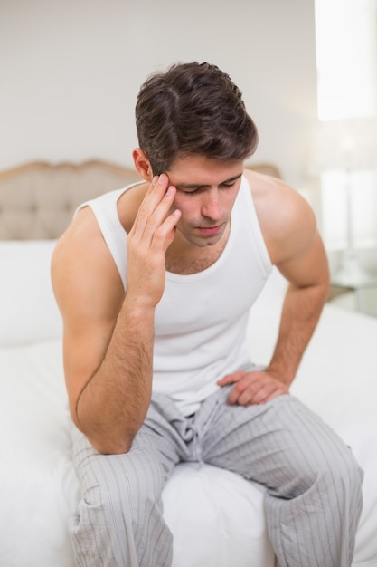 Jeune homme souffrant de maux de tête au lit