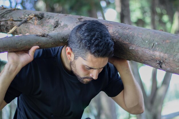 jeune homme soulevant un tronc d'arbre dans une forêt bûcheron coupant un arbre dans la forêt