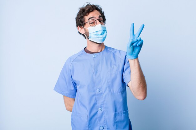 Jeune homme souriant et l'air heureux, insouciant et positif, gesticulant victoire ou paix avec une seule main. concept de coronavirus