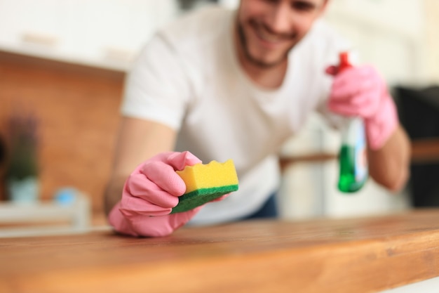 Jeune homme souriant beau nettoyage cuisine moderne.