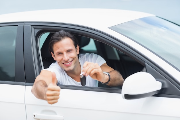 Jeune homme souriant à la caméra montrant la clé