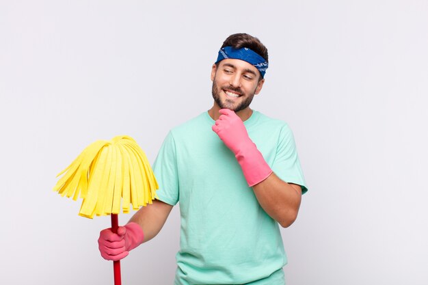 Photo jeune homme souriant avec une expression heureuse et confiante avec la main sur le menton, se demandant et regardant sur le côté