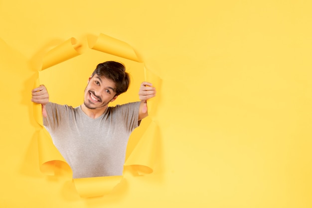 jeune homme souriant sur fond de papier jaune déchiré type intérieur du visage