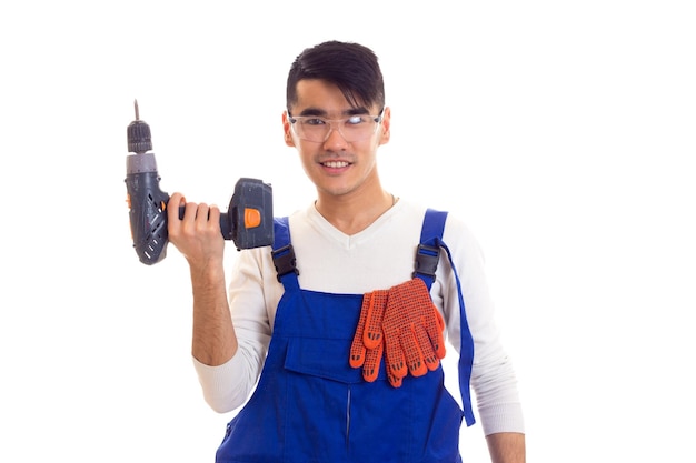 Jeune homme souriant avec des gants orange et des lunettes de protection tenant un tournevis électrique