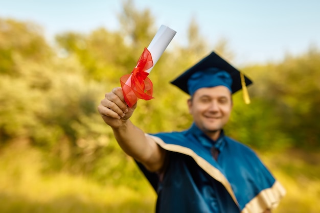 Un jeune homme souriant et heureux célèbre son diplôme et son doctorat. célébrer le concept de remise des diplômes