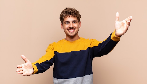 Jeune homme souriant joyeusement donnant un câlin de bienvenue chaleureux, amical, aimant, se sentant heureux et adorable