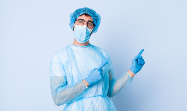 Jeune homme souriant joyeusement et pointant vers le côté et vers le haut avec les deux mains montrant l'objet dans l'espace de copie. concept de coronavirus