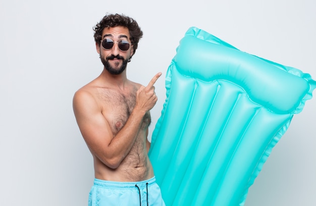 Jeune homme souriant joyeusement et regardant de côté, se demandant, pensant ou ayant une idée