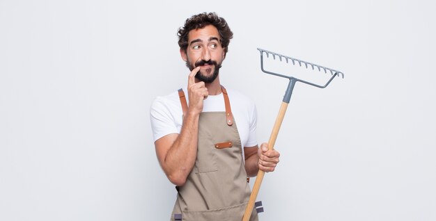 Jeune homme souriant joyeusement et rêvassant ou doutant, regardant sur le côté