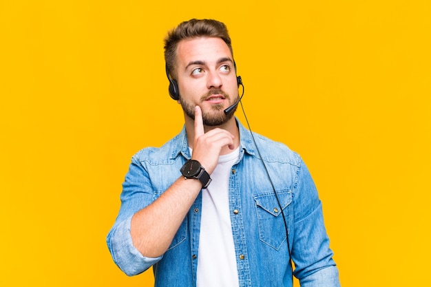 Jeune homme souriant joyeusement et rêvassant ou doutant, regardant sur le côté