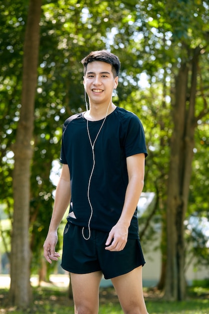 Un jeune homme souriant joyeux asiatique heureux pendant le jogging du matin à l'extérieur. Fitness, sport, exercice de crossfit et concept d'entraînement.