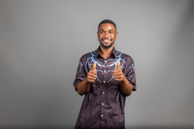 Photo jeune homme souriant largement regardant heureux positif confiant et réussi avec les deux pouces vers le haut