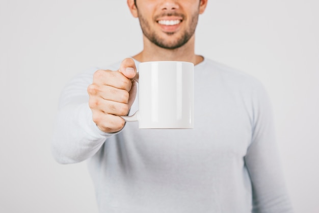 Photo jeune homme souriant offrant une tasse de café