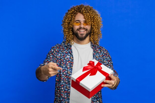 Un jeune homme souriant présente un cadeau d'anniversaire une boîte de cadeaux tend les mains promotion de vente à prix réduit