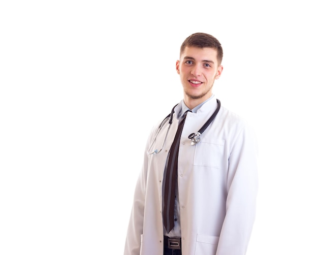 Jeune homme souriant en robe de médecin avec stéthoscope sur son cou sur fond blanc en studio